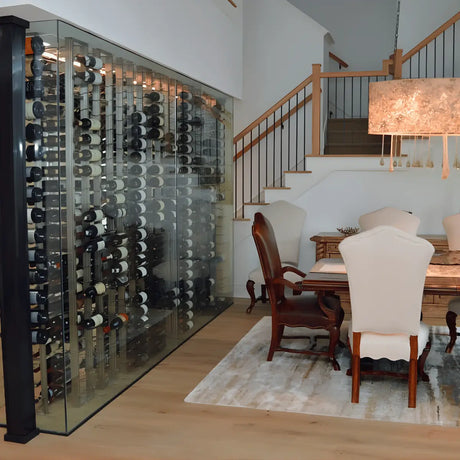 Residential glass wine cellar with floor-to-ceiling racks integrated into a modern dining and living space